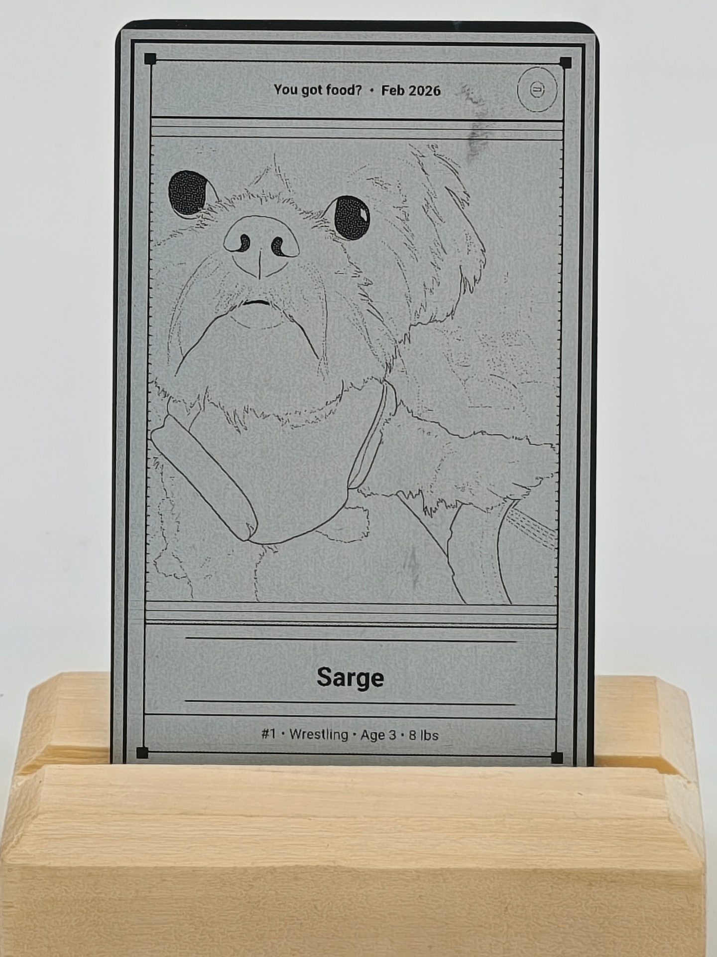 Engraved metal keepsake card with a portrait of a small dog, displayed on a maple stand
